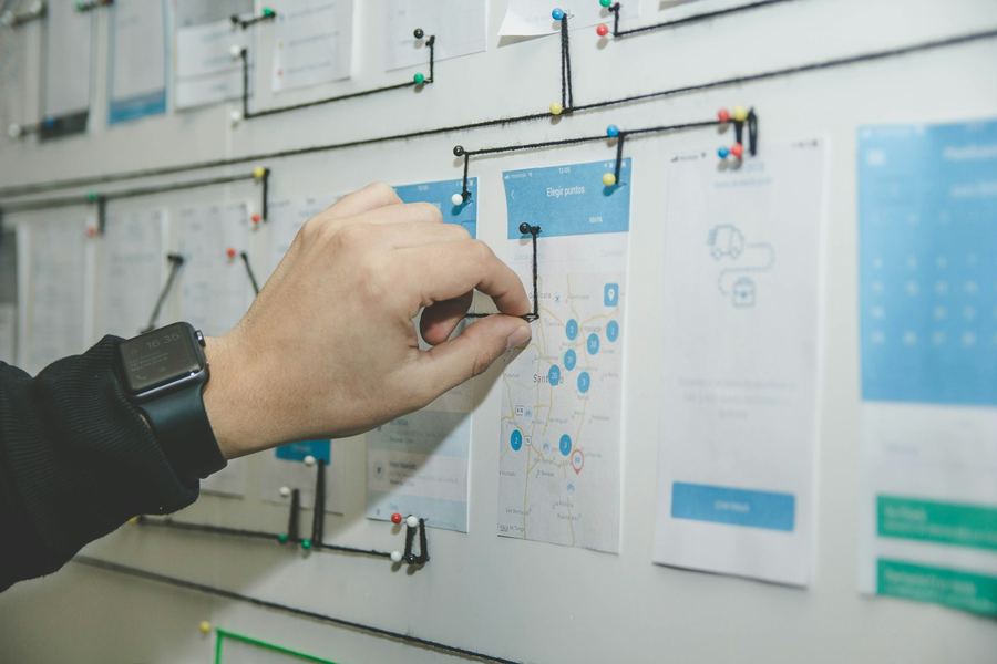 A hand pinning workflow screens onto a planning board